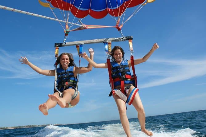 Two passengers parasailing above the sea while being towed by a boat